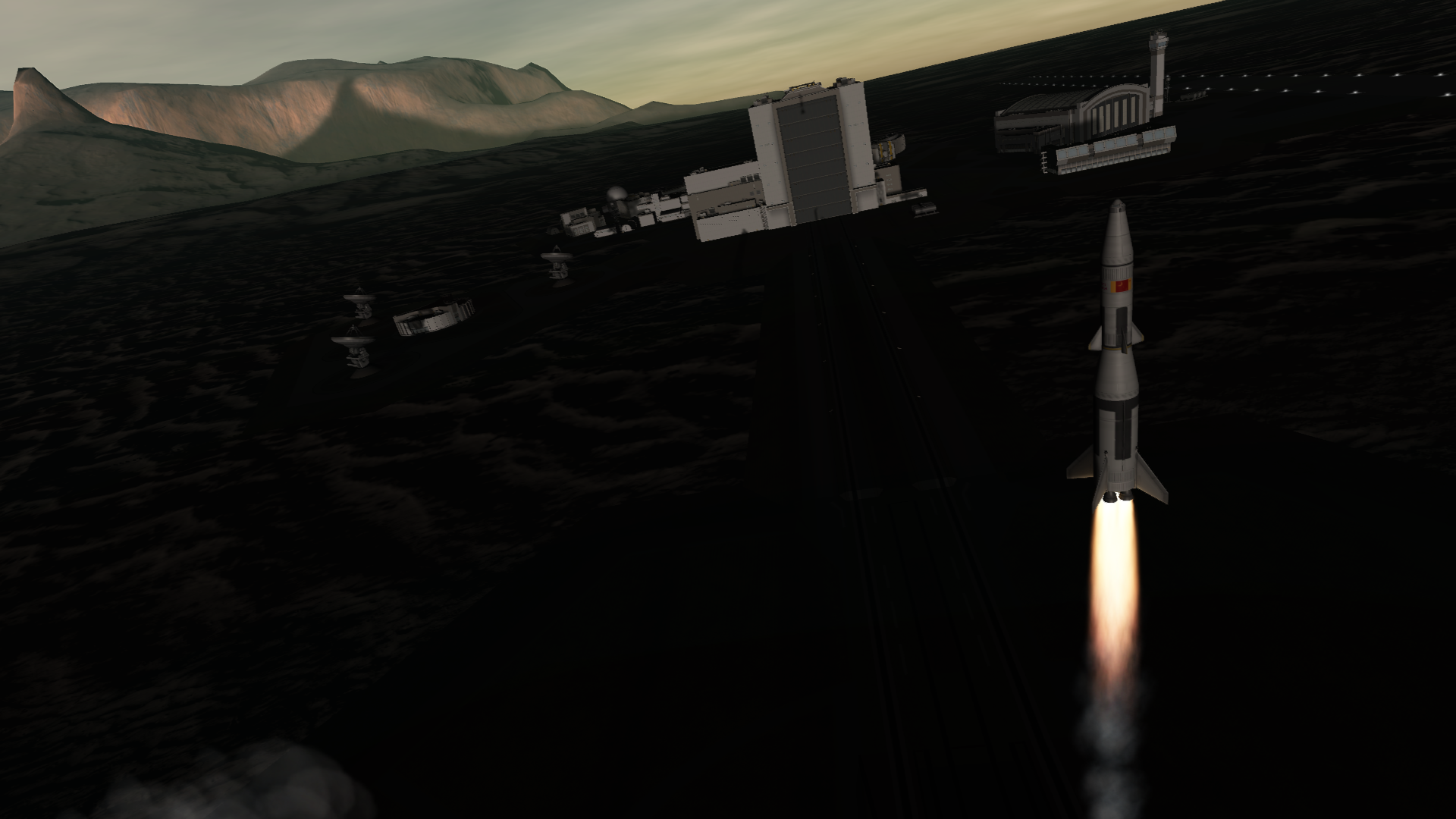 A fourth iteration on the same rocket, this time with the camera aimed to showcase the buildings of the space center. The triangle of arrays that make up the tracking station, the rectangular vehicle assembly building, the huge windows of mission control, and the wide spaceplane hangar with its air control tower are all visible.