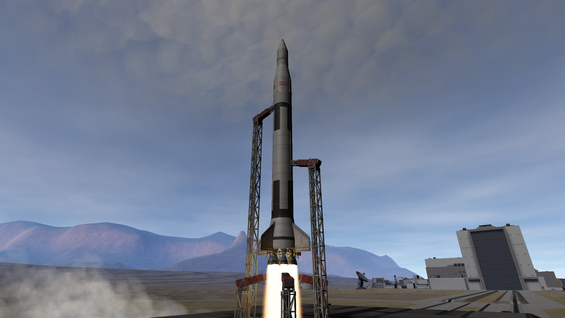 A tall rocket, with a stepped layout of a small upper section with a nosecone, a wide and very long middle, and a widening bottom with fins and a ring of eight engines; lifts off from the pad.